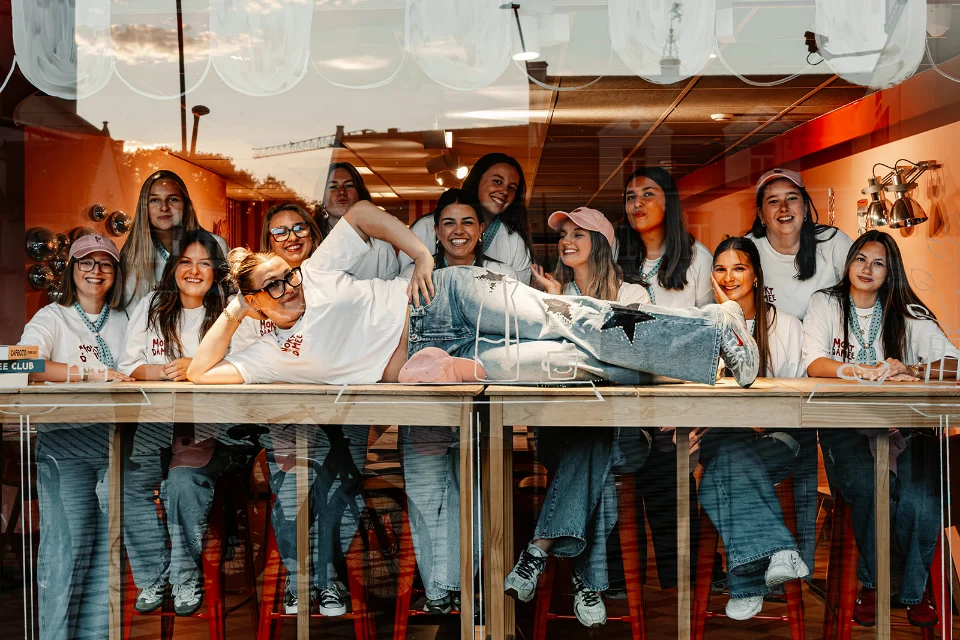 Het Moktdamee-team poseert samen aan het raam